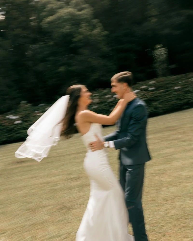 A bride and groom embracing on a lawn, softly blurred with motion