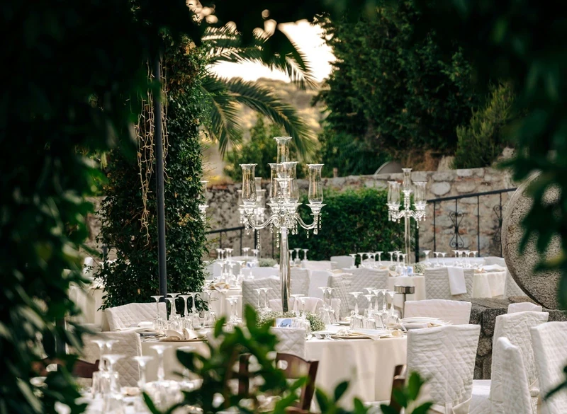 Outdoor wedding dinner tables with candelabras among greenery